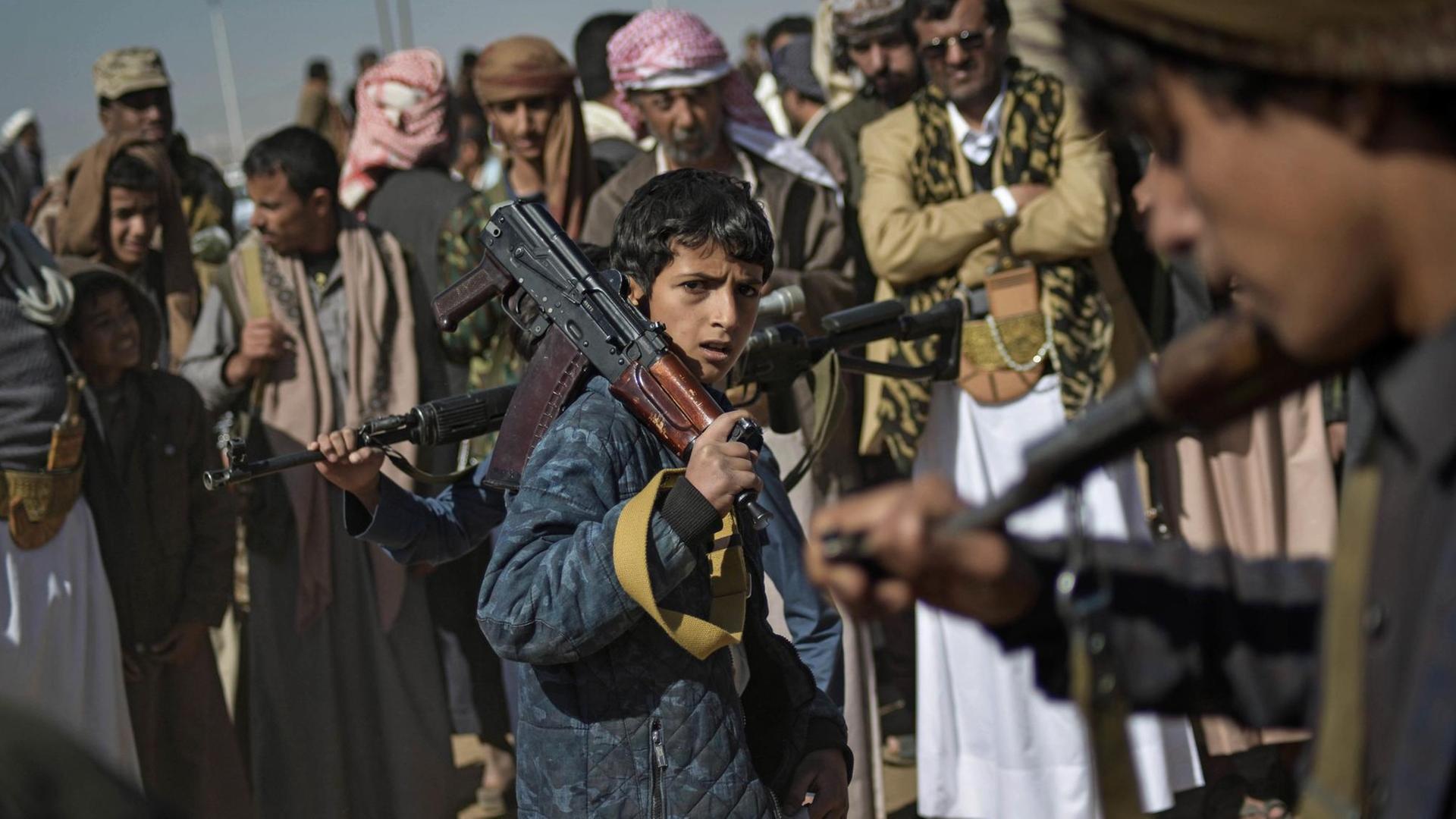Ein Junge trägt auf einer Rekrutierungsversammlung für neue Kämpfer der Huthi-Rebellen in Sanaa (Jemen) ein Gewehr über der Schulter.
