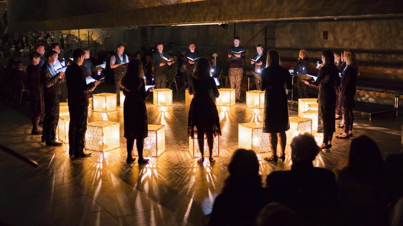 Das Ensemble steht im Kreis, im Kreisinneren stehen leuchtende Lampen. Das Ensemble steht im Kreis, im Kreisinneren stehen leuchtende Lampen.