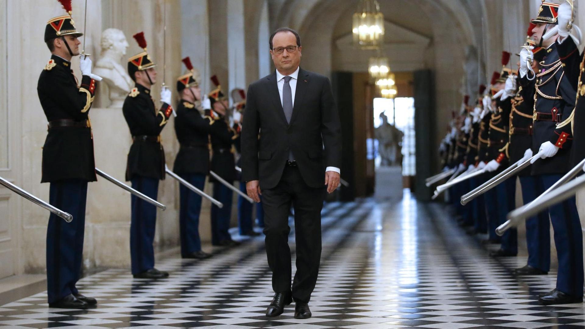 Hollande läuft einen Gang entlang. Rechts und links salutieren Mitglieder einer Garde mit Schwertern. Hollande läuft einen Gang entlang. Rechts und links salutieren Mitglieder einer Garde mit Schwertern.