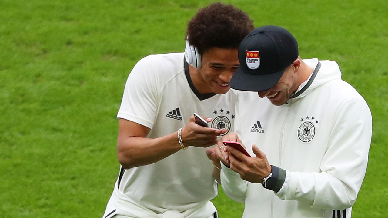 Leroy Sane (l.) und Lukas Podolski zeigen sich etwas auf dem Smartphone. Leroy Sane (l.) und Lukas Podolski zeigen sich etwas auf dem Smartphone.