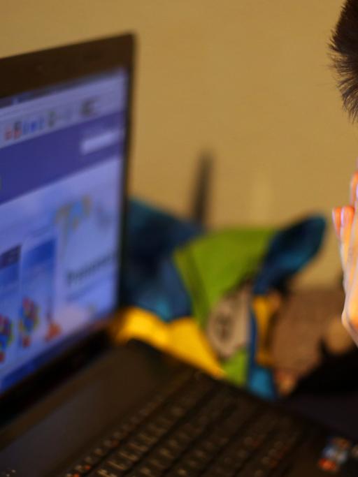 Ein Junge reibt sich am 15.05.2013 vor seinem Laptop beim betrachten der Facebook-Seite die Augen.
