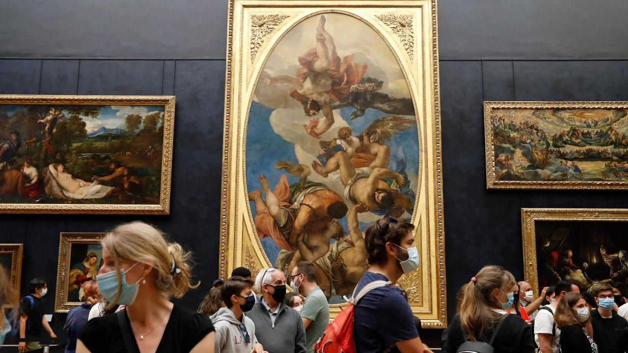 Besucher tragen Mundschutze während sie die Ausstellung im Museum Louvre besuchen. Besucher tragen Mundschutze während sie die Ausstellung im Museum Louvre besuchen.