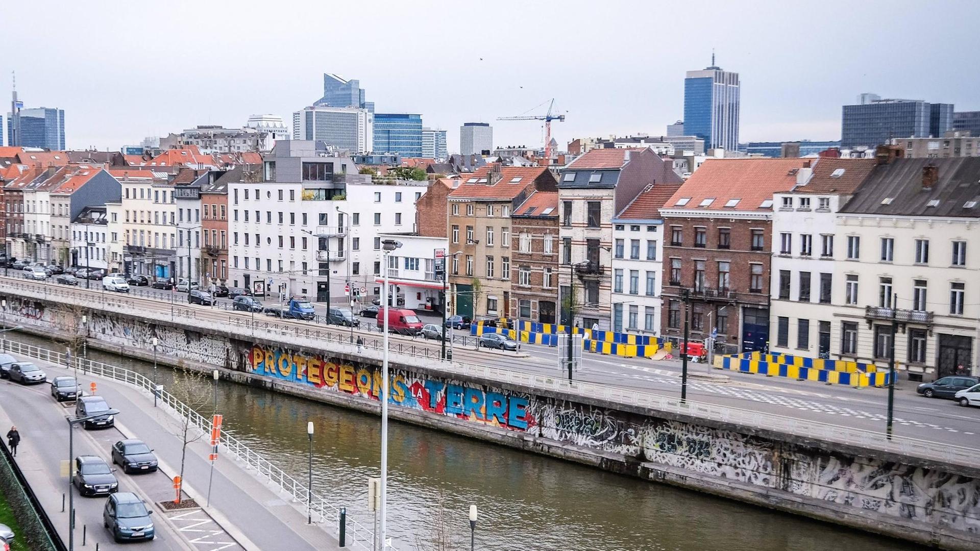 Eine Panoramaansicht des Stadtviertels Molenbeek in der belgischen Stadt Brüssel, hinter einer Straße ist ein Kanal und dahinter Häuser zu sehen.