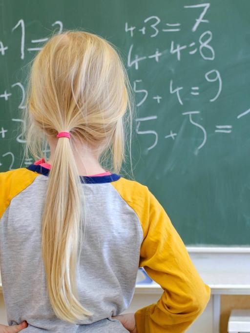 Ein Schulkind steht nachdenklich vor Gleichungen an einer Schultafel in Dresden