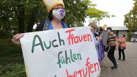 Demonstrantin vor der Regionalkonferenz des Synodalen Weges in Ludwigshafen. Sie trägt ein Transparent mit der Aufschrift "Auch Frauen fühlen sich berufen". © Synodaler Weg / Klaus Landry