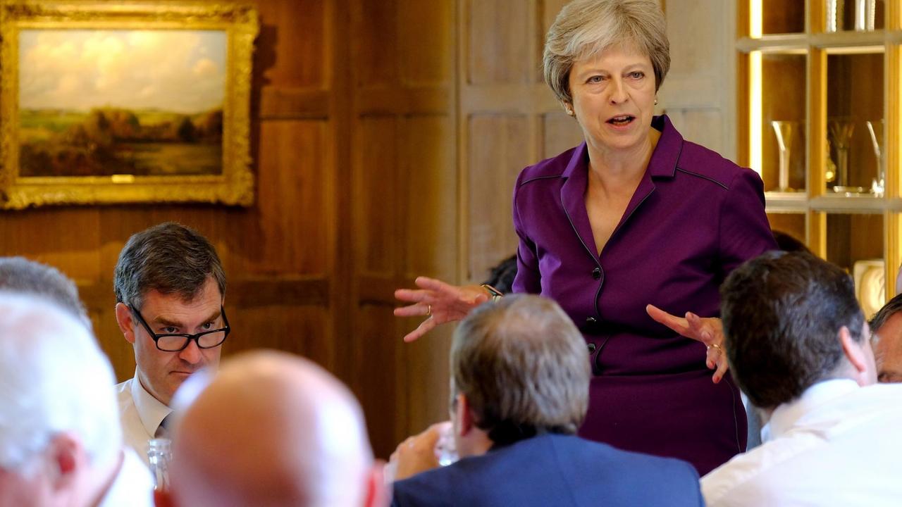 Die britische Premierministerin Theresa May spricht auf einer Sitzung des britischen Kabinetts auf dem Landsitz Chequers. Im Vordergrund Köpfe von Kabinettsmitgliedern von hinten gesehen.