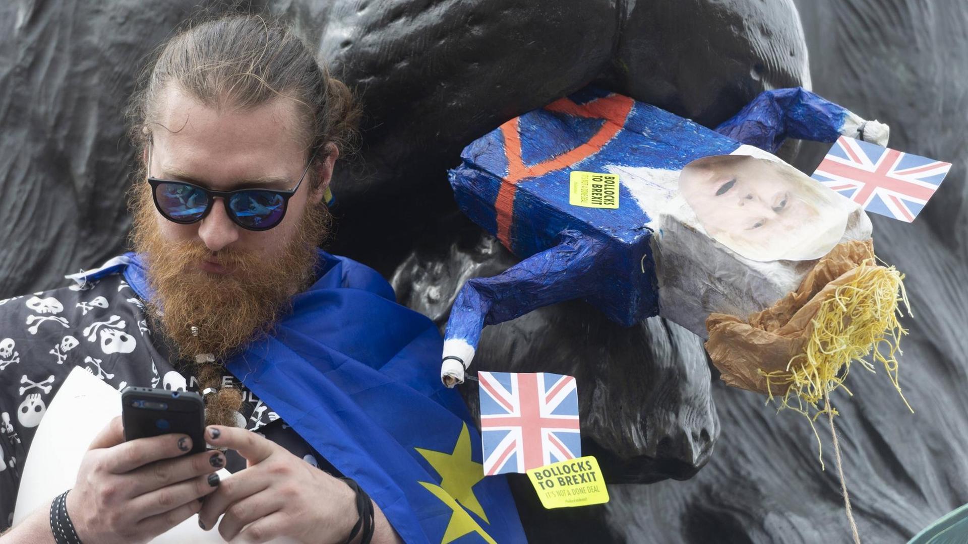 Ein Anti-Brexit-Demonstrant am Trafalgar Square in London verfüttert symbolisch den britischen Premierminister Boris Johnson an eine Löwenskulptur. Ein Anti-Brexit-Demonstrant am Trafalgar Square in London verfüttert symbolisch den britischen Premierminister Boris Johnson an eine Löwenskulptur.
