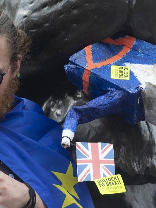 Ein Anti-Brexit-Demonstrant am Trafalgar Square in London verfüttert symbolisch den britischen Premierminister Boris Johnson an eine Löwenskulptur.