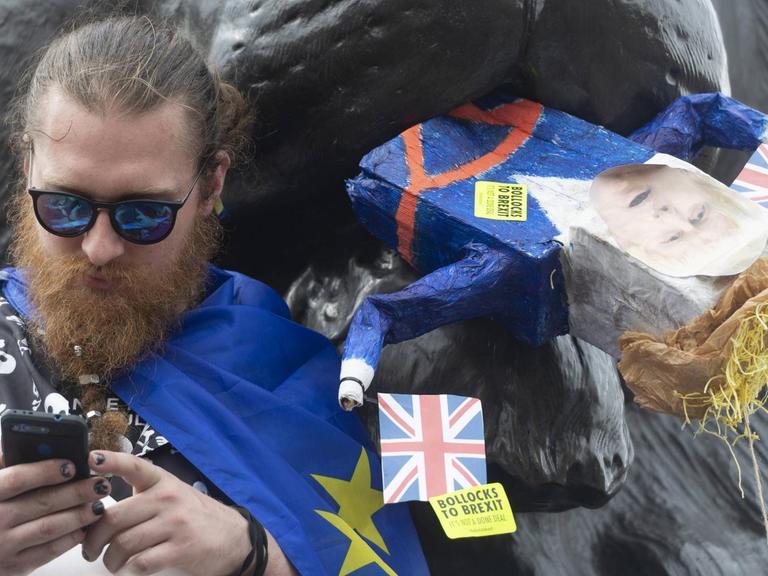 Ein Anti-Brexit-Demonstrant am Trafalgar Square in London verfüttert symbolisch den britischen Premierminister Boris Johnson an eine Löwenskulptur.