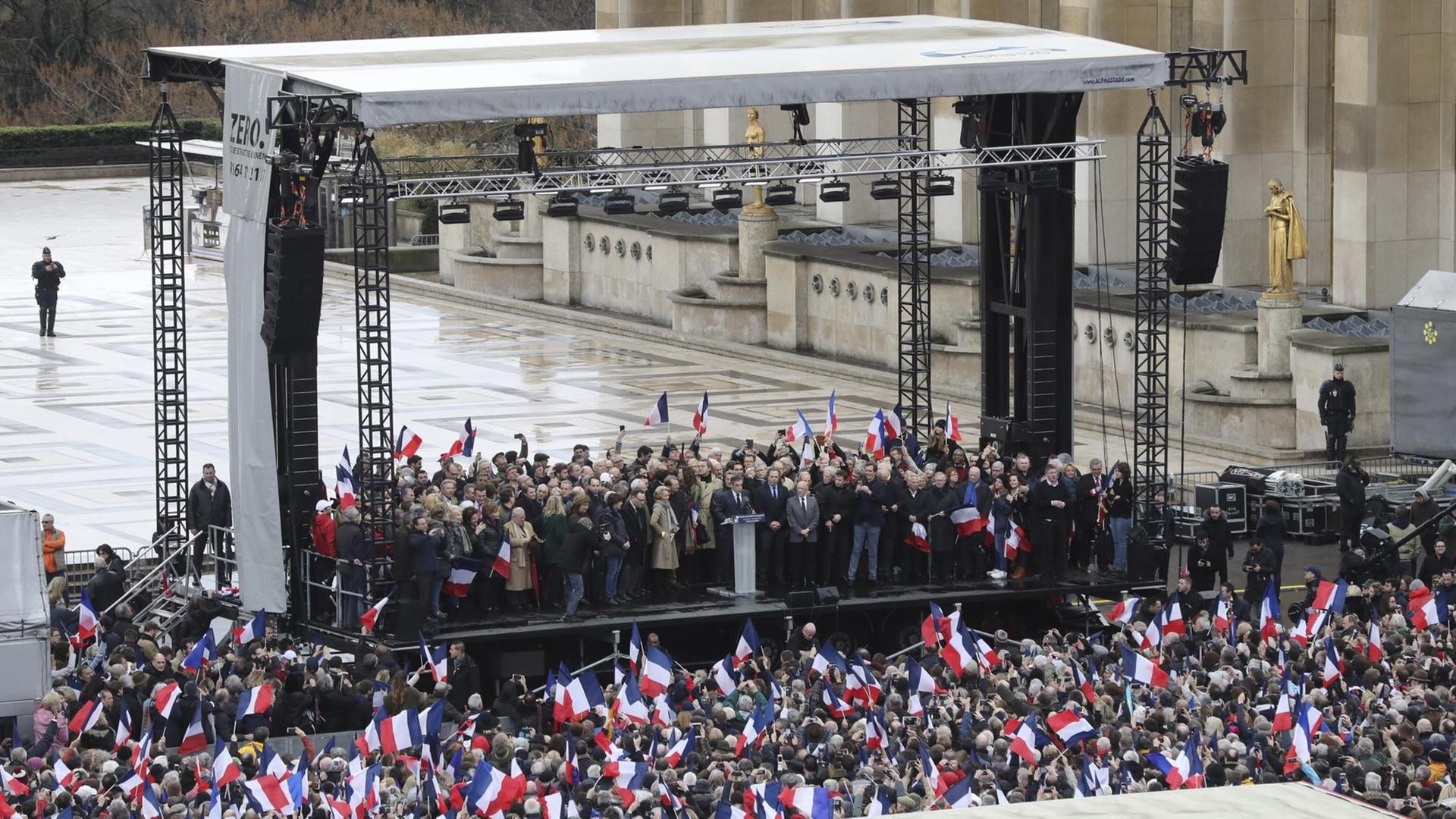 Sie sehen eine Tribüne und davor eine Menschenmenge auf dem Trocadero-Platz in Paris. Der Politiker François Fillon hält eine Rede. Sie sehen eine Tribüne und davor eine Menschenmenge auf dem Trocadero-Platz in Paris. Der Politiker François Fillon hält eine Rede.