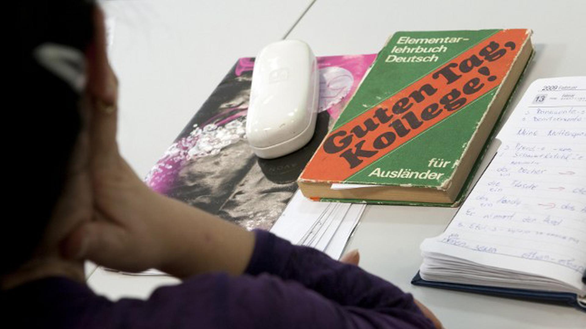 Ein Mädchen sitzt vor einem Schreibtisch mit einem Deutschbuch für Ausländer. Ein Mädchen sitzt vor einem Schreibtisch mit einem Deutschbuch für Ausländer.