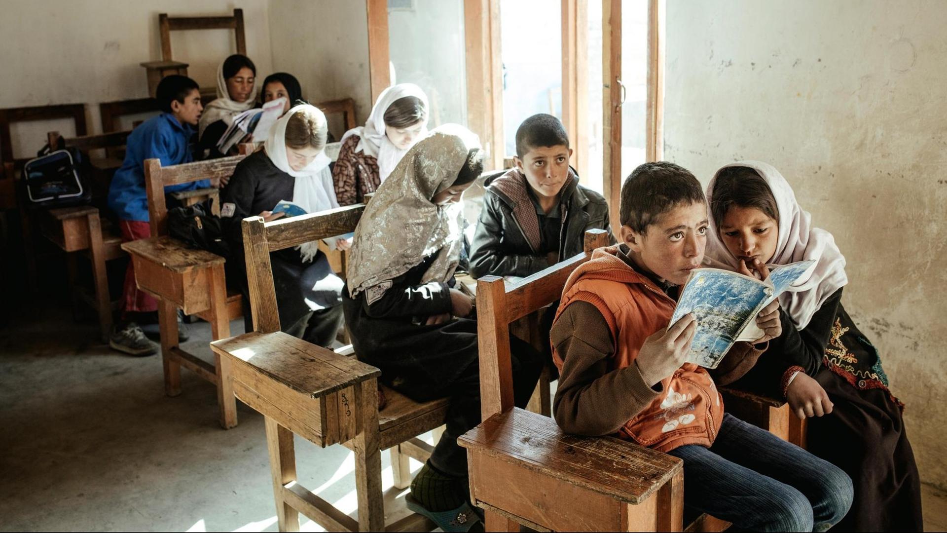 Schule in Afghanistan: Ein Mädchen und ein Junge lesen gemeinsam aus einem Heft. Schule in Afghanistan: Ein Mädchen und ein Junge lesen gemeinsam aus einem Heft.