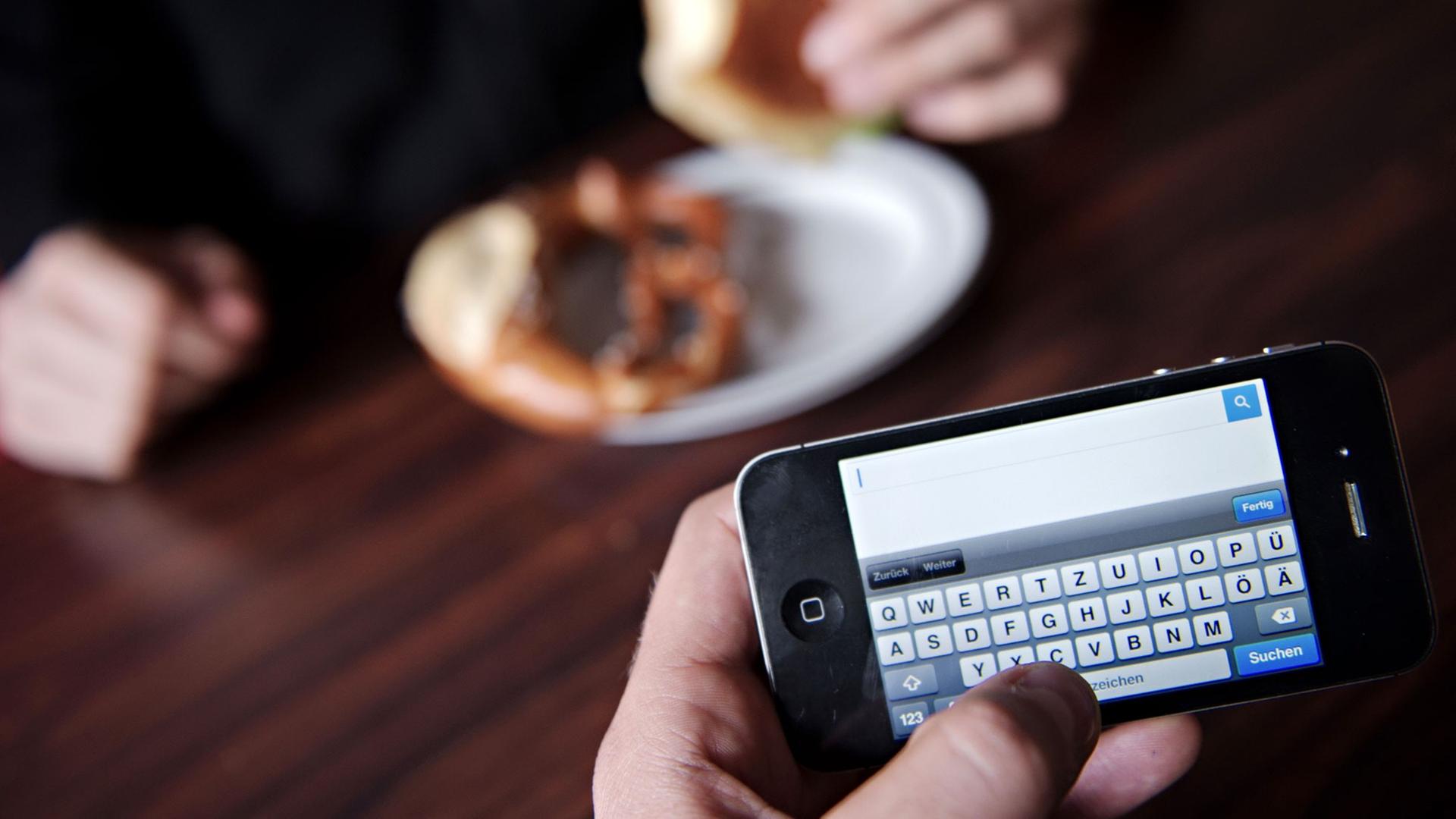 Ein Mann surft mit seinem Smartphone im Internet. Fast neun von zehn Deutschen finden es unhöflich, wenn ihr Gegenüber beim Essen immer wieder auf das Smartphone schaut. Foto: Nicolas Armer Ein Mann surft mit seinem Smartphone im Internet. Fast neun von zehn Deutschen finden es unhöflich, wenn ihr Gegenüber beim Essen immer wieder auf das Smartphone schaut. Foto: Nicolas Armer