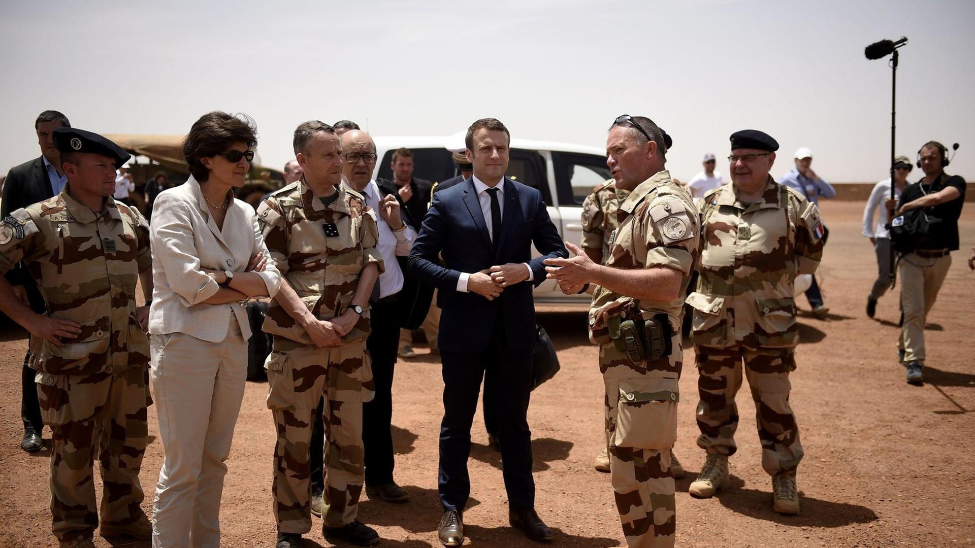 Frankreichs Präsedent Emmanuel Macron (im blauen Anzug) steht am 9. Mai 2017 mit der Verteidigungsministerin Sylvie Goulard (2. v.l.) zwischen Soldaten der französischen Anti-Terror-Operation "Barkhane" in Gao im norden von Mali. Frankreichs Präsedent Emmanuel Macron (im blauen Anzug) steht am 9. Mai 2017 mit der Verteidigungsministerin Sylvie Goulard (2. v.l.) zwischen Soldaten der französischen Anti-Terror-Operation "Barkhane" in Gao im norden von Mali.