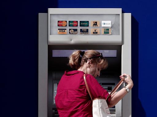 Eine Frau steht vor einem Geldautomaten der griechischen Eurobank.