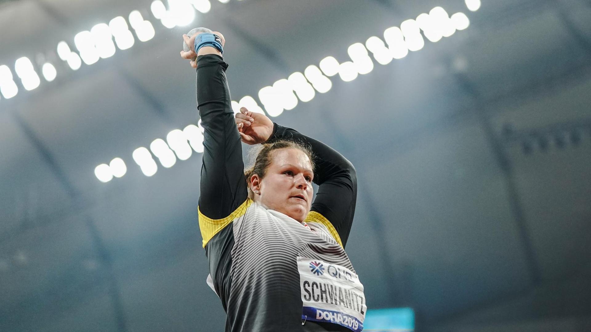 Aus Froschperspektive sieht man die Kugelstoßerin Christina Schwanitz in einem Stadion die Kugel empor halten. Aus Froschperspektive sieht man die Kugelstoßerin Christina Schwanitz in einem Stadion die Kugel empor halten.