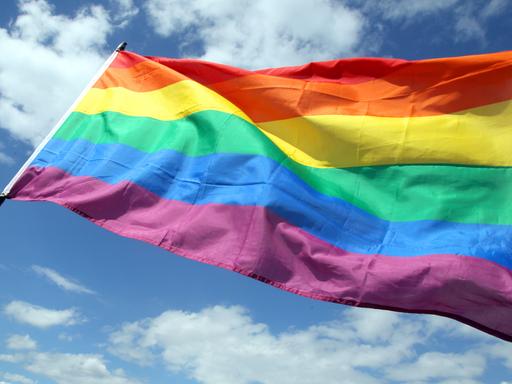Es ist die Regenbogenfahne zu sehen, die ein Symbol der Schwulen- und Lesbenbewegung ist.