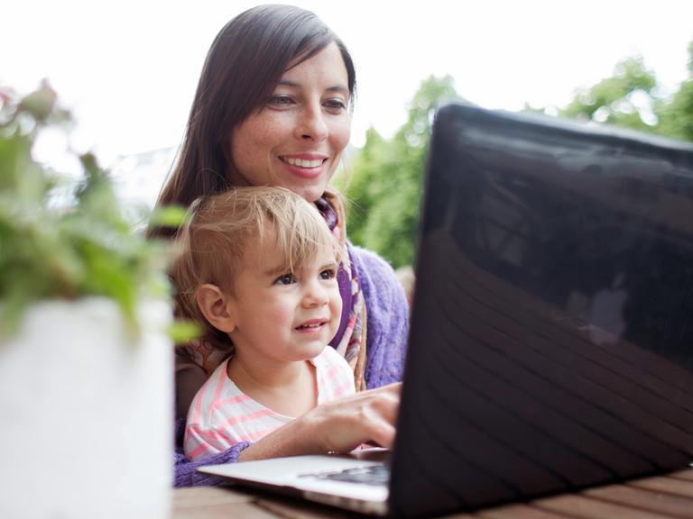 Die Anwältin Sandra Runge sitzt mit der zweijährigen Ada vor einem Laptop