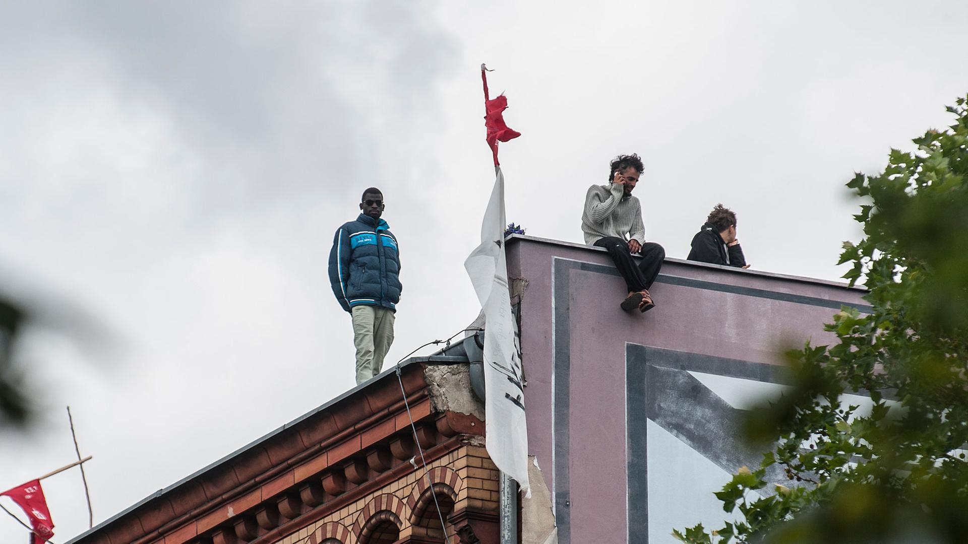 Flüchtlinge stehen auf dem Dach der besetzten ehemaligen Gerhart-Hauptmann-Schule. Flüchtlinge stehen auf dem Dach der besetzten ehemaligen Gerhart-Hauptmann-Schule.