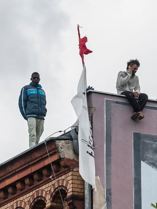 Flüchtlinge stehen auf dem Dach der besetzten ehemaligen Gerhart-Hauptmann-Schule.
