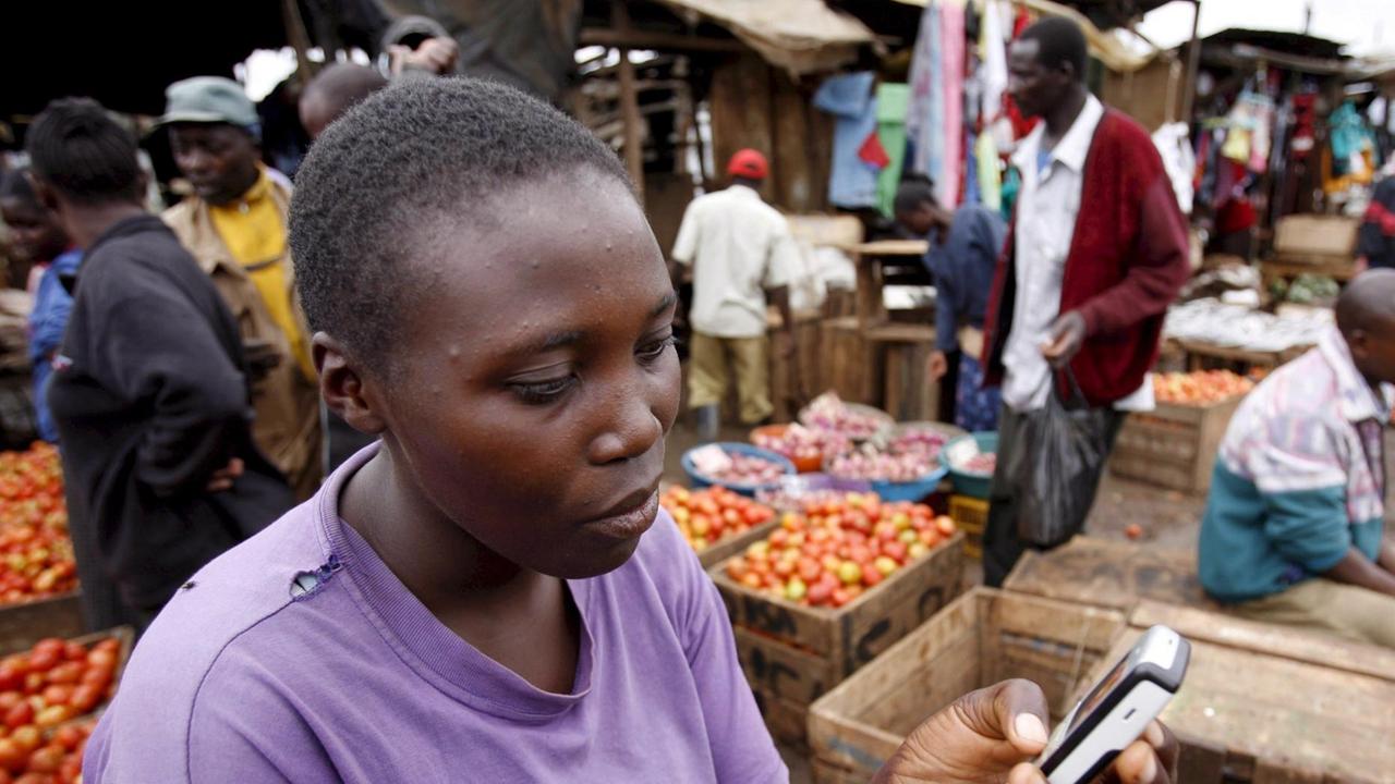 Eine Verkäuferin schaut auf ihr Mobiltelefon auf dem Markt in Nairobi.