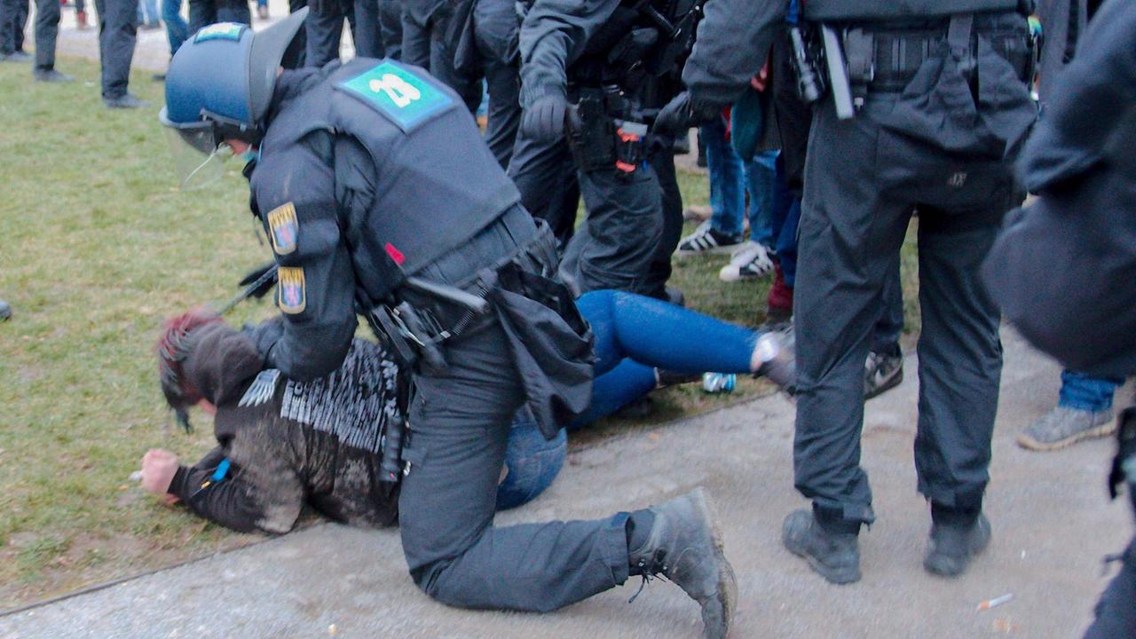 Ein Polizist hält einen Demonstranten am Boden, umgeben von weiteren Polizisten. Ein Polizist hält einen Demonstranten am Boden, umgeben von weiteren Polizisten.