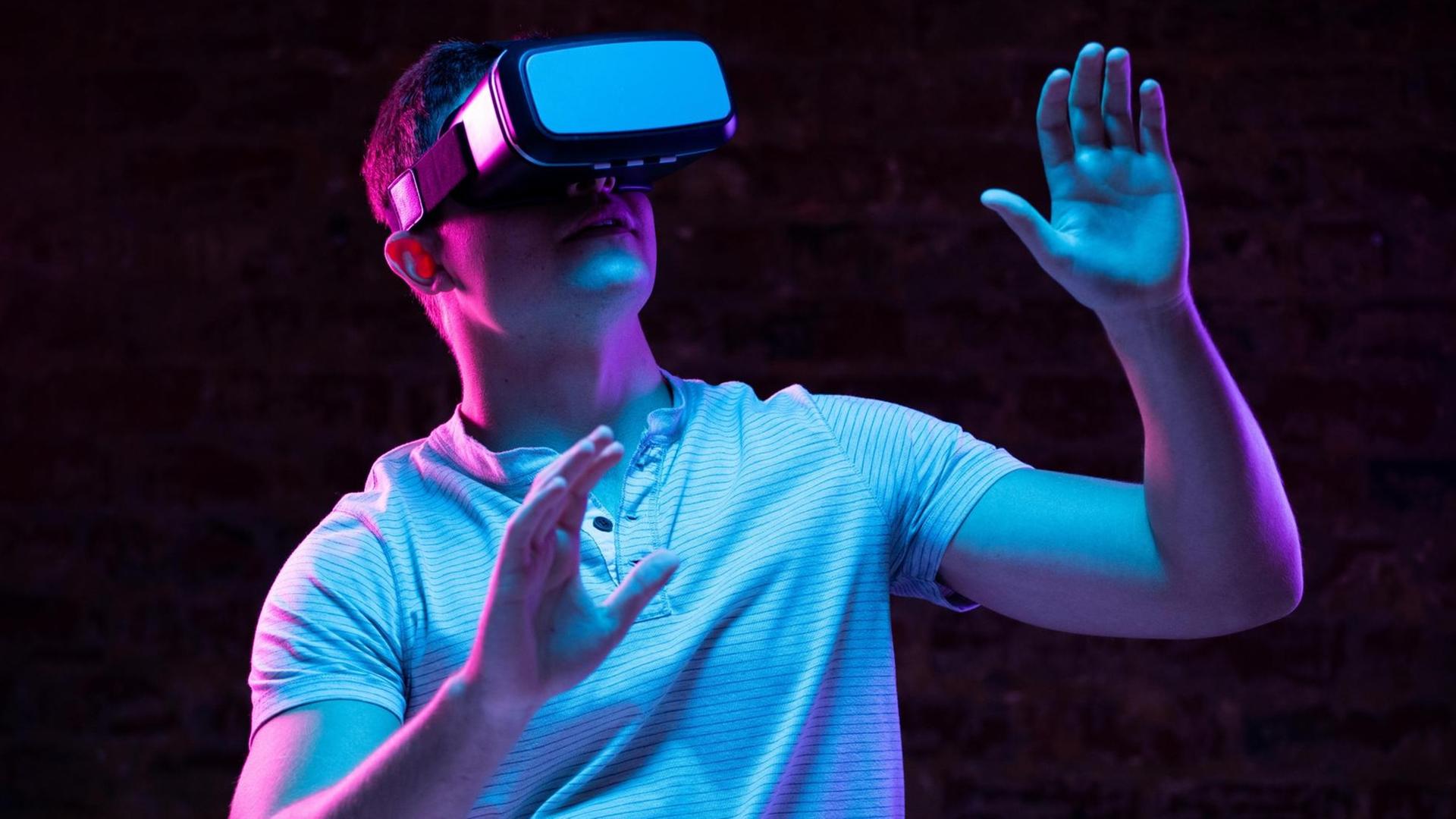 Ein Mann steht ein einem dunklen Raum trägt eine VR-Brille. Ein Mann steht ein einem dunklen Raum trägt eine VR-Brille.