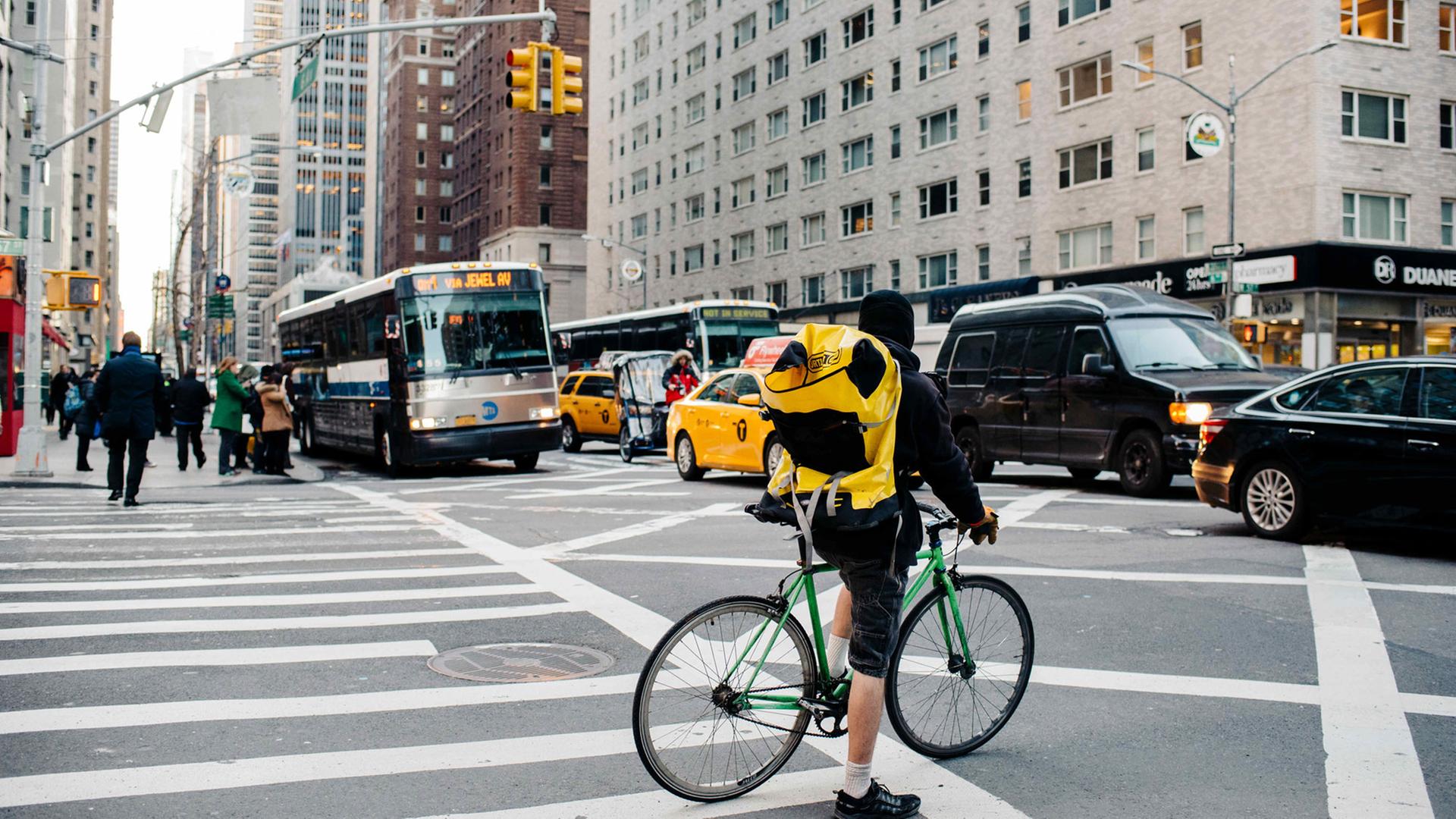 Ein Fahrradkurier wartet am 02.03.2016 an einer Ampel in Midtown Manhattan in New York (USA) auf den vorbeirollenden Verkehr Ein Fahrradkurier wartet am 02.03.2016 an einer Ampel in Midtown Manhattan in New York (USA) auf den vorbeirollenden Verkehr