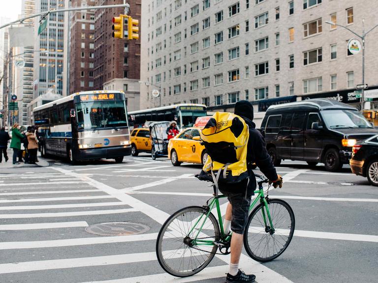 Ein Fahrradkurier wartet am 02.03.2016 an einer Ampel in Midtown Manhattan in New York (USA) auf den vorbeirollenden Verkehr