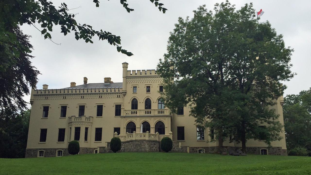 Frontansicht von Schloss Reichenow in Brandenburg auf einer Wiese. Frontansicht von Schloss Reichenow in Brandenburg auf einer Wiese.