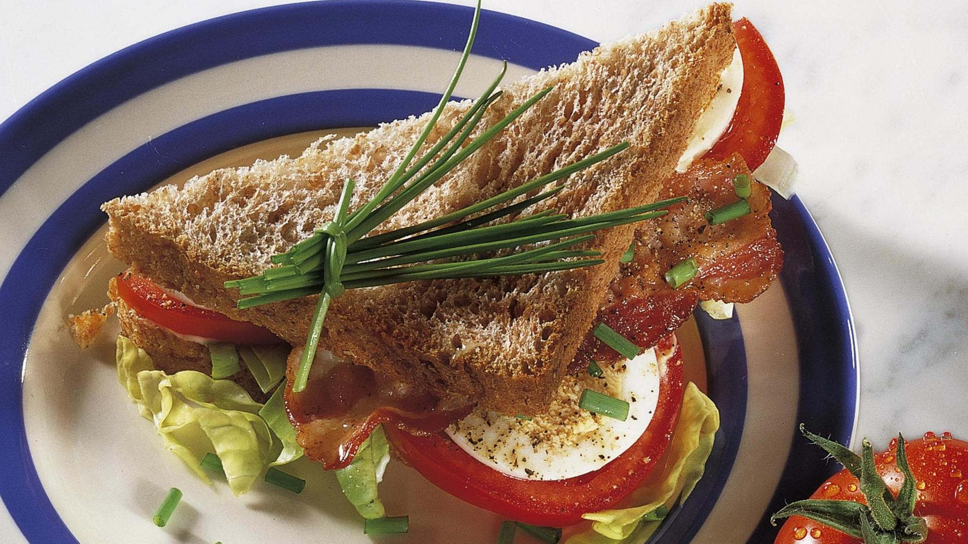 Sandwich mit Speck, Salatblättern und Tomaten