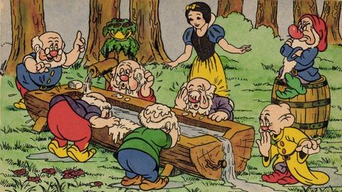 Ausschnitt aus "Schneewitchen" nach Walt Disney: Schneewitchen bewirtet die sieben Zwerge an einem Tisch im Wald.