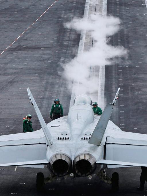 Auf dem Flugzeugträger "USS Ronald Reagan" steht ein Kampfjet, daneben sind einige Menschen zu sehen.