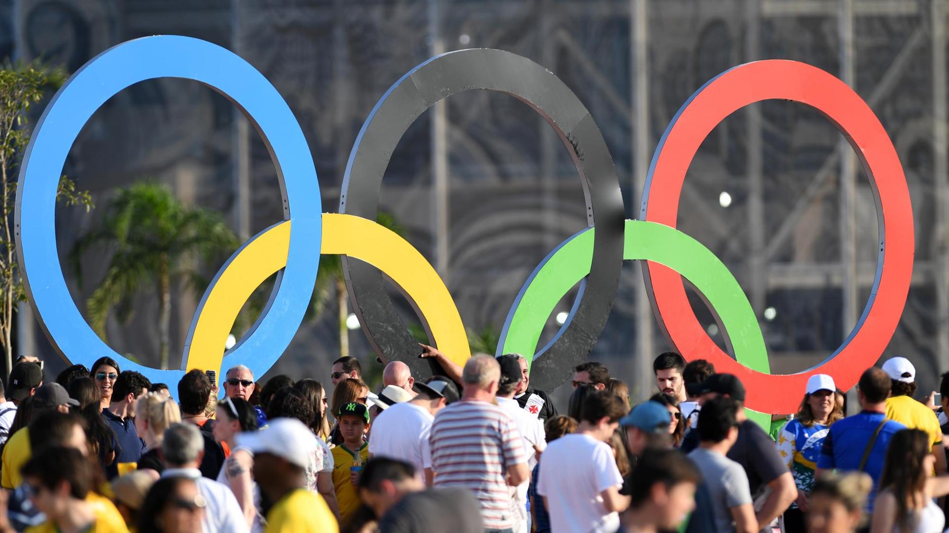 Viele Besucher stehen vor den Olympischen Ringen im Olympiapark Barra in Rio de Janeiro.