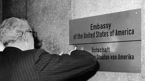 John Sherman Cooper, der amerikanische Botschafter in der DDR, befestigt am 9. Dezember 1974 am vorläufigen Botschaftsgebäude in Ost-Berlin das Messingschild.