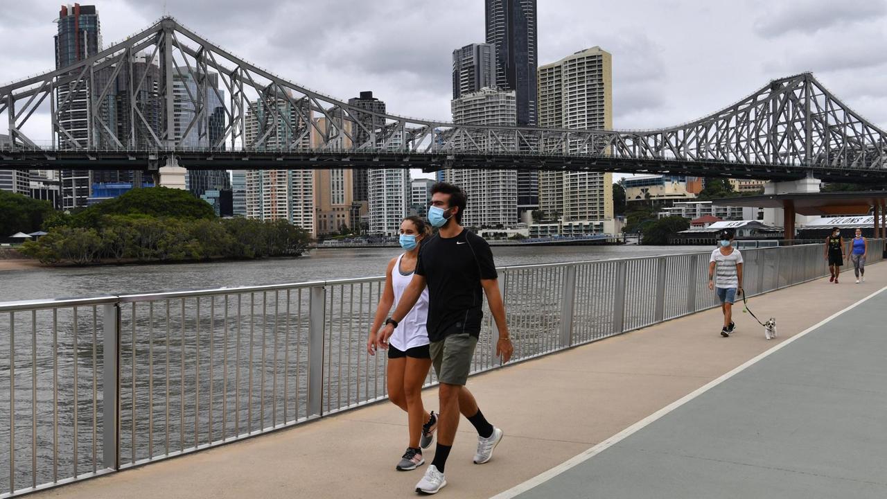 Menschen mit Mund-Nasen-Bedeckung laufen im australischen Brisbane an einem Fluss entlang. Menschen mit Mund-Nasen-Bedeckung laufen im australischen Brisbane an einem Fluss entlang.