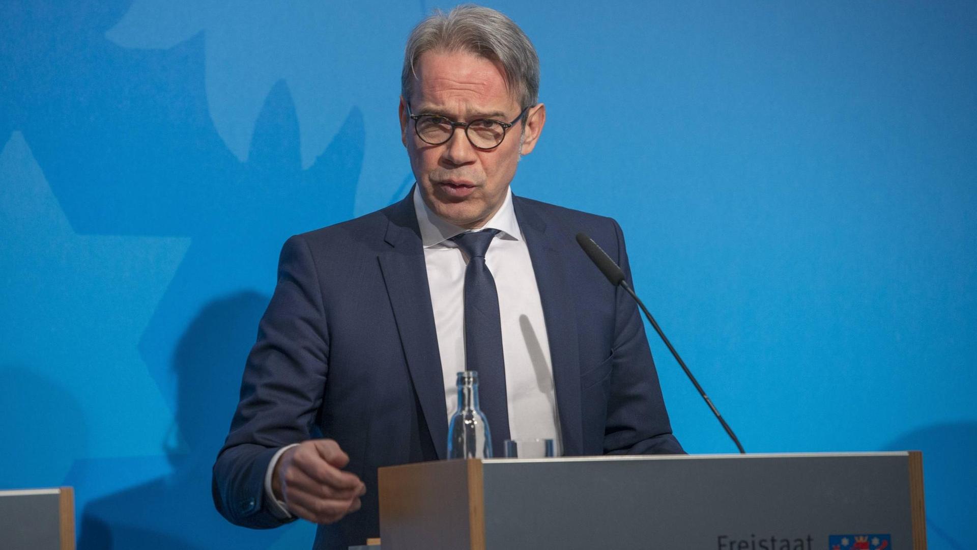 Maier steht an einem Rednerpult mit der Aufschrift "Freistaat Thüringen" und dem Logo des Freistaats.