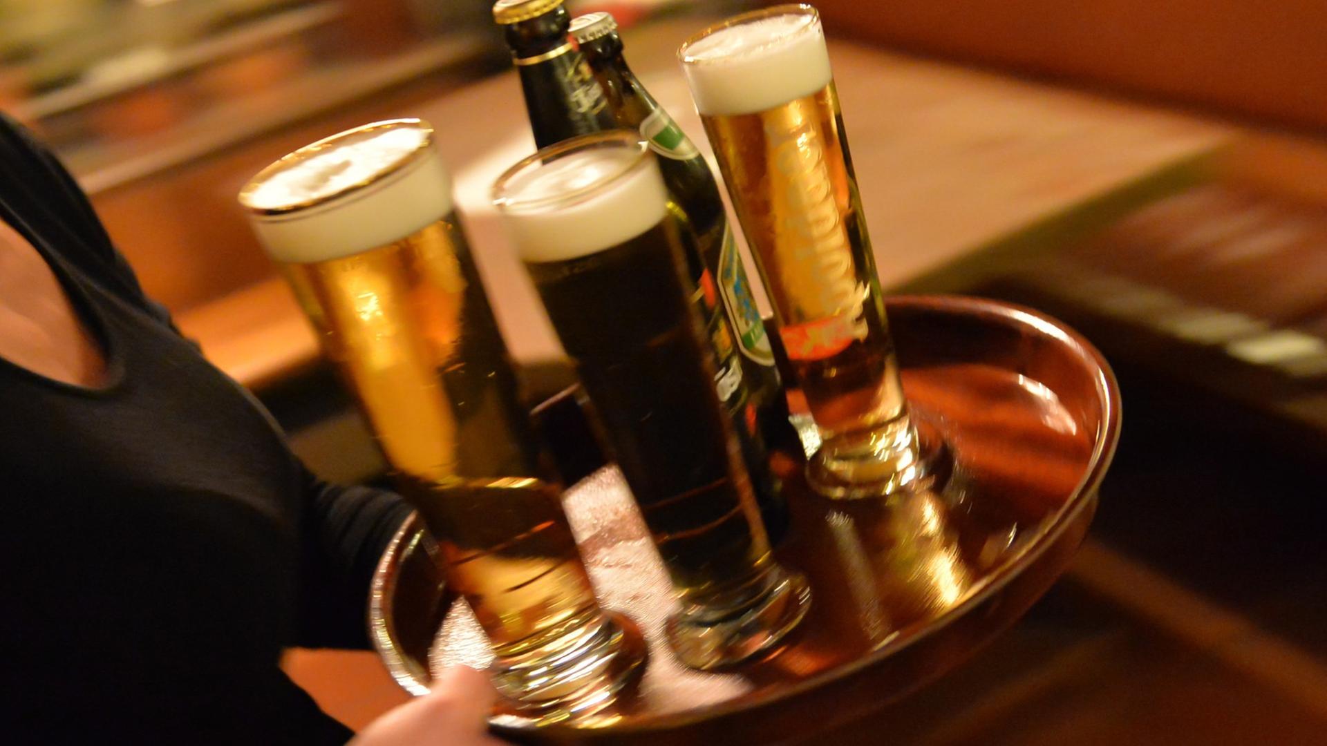 Eine Bedienung trägt am 29.10.2013 in Erfurt (Thüringen) in einem Lokal ein Tablett mit Bier. Eine Bedienung trägt am 29.10.2013 in Erfurt (Thüringen) in einem Lokal ein Tablett mit Bier.