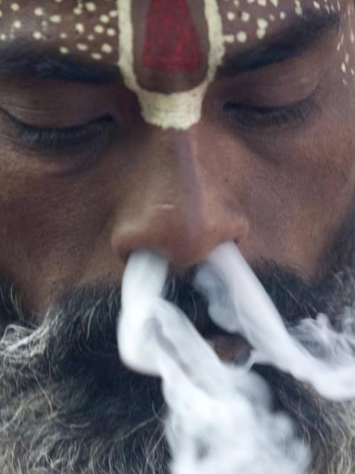 Einem Hindu Priester strömt Rauch aus beiden Nasenlöchern, Kathmandu, Nepal.