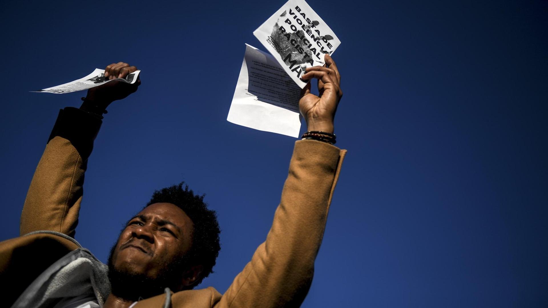 Ein Mann hält ein Papier hoch mit der Aufschrift "Genug von rassistischer Polizeigewalt" während einer Demonstration gegen Rassismus und Missbrauch von polizeilicher Gewalt in Seixal, einem Vorort von Lissabon, am 25. Januar 2019