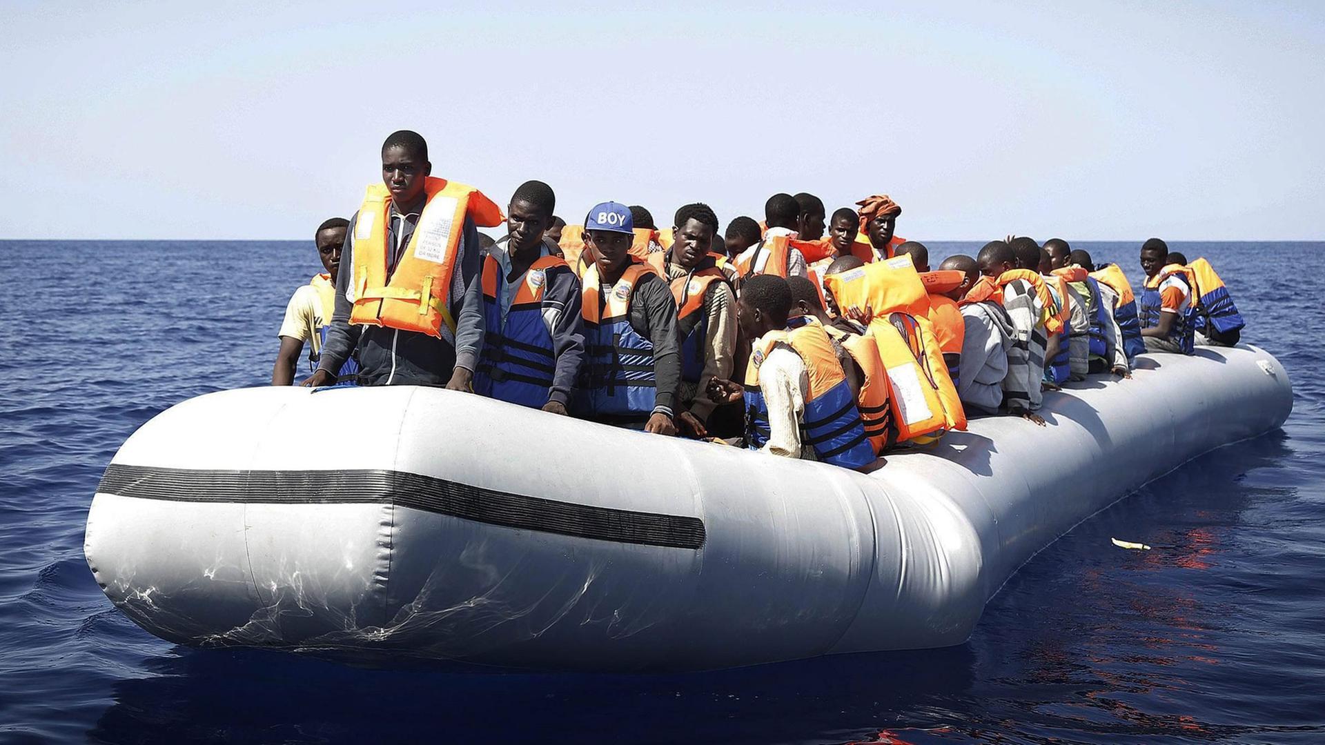 Flüchtlinge aus Afrika stehen in einem Schlauchboot, das im Mittelmeer treibt - sie werden schließlich von einem italienischen Rettungsschiff geborgen. Flüchtlinge aus Afrika stehen in einem Schlauchboot, das im Mittelmeer treibt - sie werden schließlich von einem italienischen Rettungsschiff geborgen.