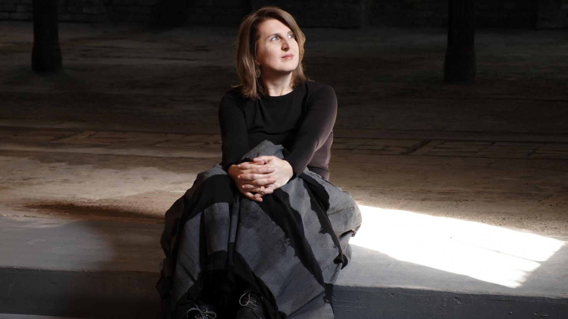 Die Musikerin Maja Mijatovic sitzt auf einer Treppe im Halbdunkeln und schaut ins Licht Die Musikerin Maja Mijatovic sitzt auf einer Treppe im Halbdunkeln und schaut ins Licht