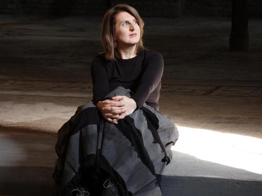 Die Musikerin Maja Mijatovic sitzt auf einer Treppe im Halbdunkeln und schaut ins Licht