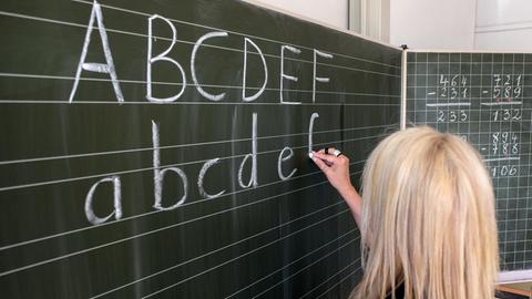 Eine Grundschullehrerin schreibt am 15.06.2015 in Hamburg die ersten Buchstaben des Alphabets auf eine Schultafel in einem Klassenzimmer.