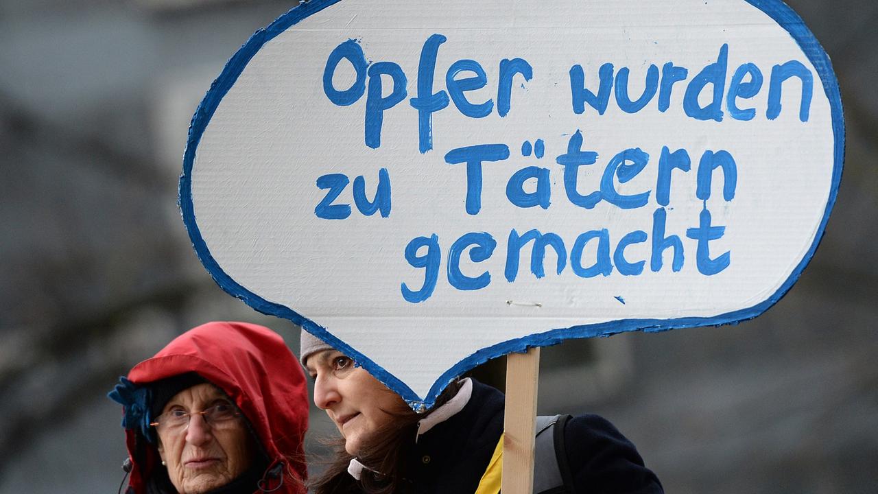 Zwei Frauen mit Schild mit der Aufschrift "Opfer wurden zu Tätern gemacht"