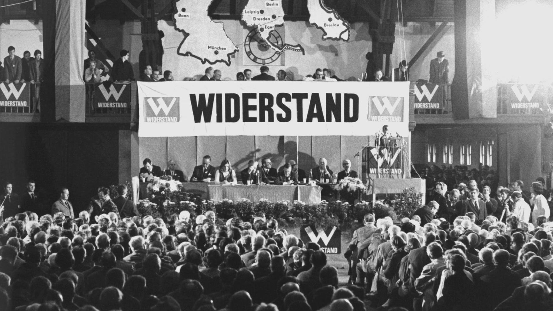 Blick in die Frankenhalle in Würzburg während der Gründungsversammlung. Unter heftigen Gegenprotesten gründeten am 31. Oktober 1970 etwa 3000 Angehörige von rechtsgerichteten Gruppen und Verbänden die vorwiegend von der NPD getragene Sammlungsbewegung Aktion Widerstand mit dem Ziel, die Ratifizierung des Moskauer Vertrages mit allen Mitteln zu verhindern und mit einem Volksbegehren Neuwahlen des Bundestages zu erzwingen. Die Teilnehmer der Versammlung formierten sich später – trotz Verbots – zu einem Demonstrationszug. Blick in die Frankenhalle in Würzburg während der Gründungsversammlung. Unter heftigen Gegenprotesten gründeten am 31. Oktober 1970 etwa 3000 Angehörige von rechtsgerichteten Gruppen und Verbänden die vorwiegend von der NPD getragene Sammlungsbewegung Aktion Widerstand mit dem Ziel, die Ratifizierung des Moskauer Vertrages mit allen Mitteln zu verhindern und mit einem Volksbegehren Neuwahlen des Bundestages zu erzwingen. Die Teilnehmer der Versammlung formierten sich später – trotz Verbots – zu einem Demonstrationszug.
