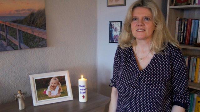 Michaela Binge steht an einem Tisch mit einem Foto ihrer verstorbenen Tochter.