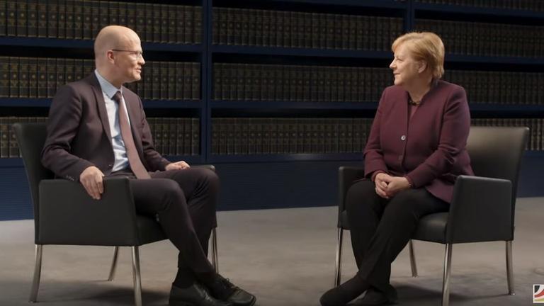 Angela Merkel und Ralph Brinkhaus sitzen einander auf einem Podium gegenüber. Angela Merkel und Ralph Brinkhaus sitzen einander auf einem Podium gegenüber.