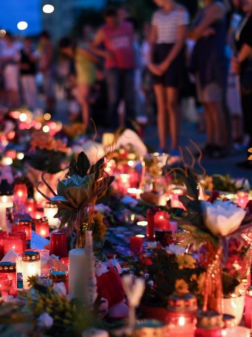 Blumen und Kerzen liegen am 24.07.2016 an der U-Bahn Station Olympia-Einkaufszentrums.