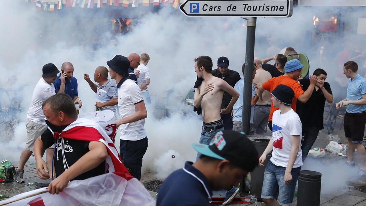 Englische Fußballfans fliehen vor Tränengas, das die französische Polizei eingesetzt hat, um Auseinandersetzungen zwischen englischen und russischen Hooligans zu beenden. Englische Fußballfans fliehen vor Tränengas, das die französische Polizei eingesetzt hat, um Auseinandersetzungen zwischen englischen und russischen Hooligans zu beenden.